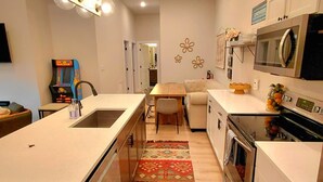 Una cocina moderna con una isla central, microondas, horno y un comedor con mesa y sillas.