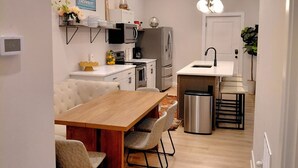 Una cocina moderna con comedor, que incluye una mesa de madera, sillas y un horno empotrado.