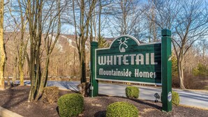 A sign for Whitetail Mountainside Homes with a natural landscape in the background. - Mountain Retreat • Ski • Tub • Trails • Golf • Arcade • Firepit (Mercersburg)
