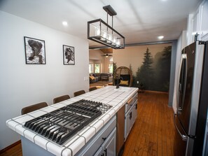 A modern kitchen with a central island, stainless steel appliances, and a dining area with a wooden floor. - Modern spacious hot tub + Deck Lake Arrowhead + Big Bear (Running Springs)