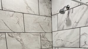 A bathroom with marble tiles and a shower.