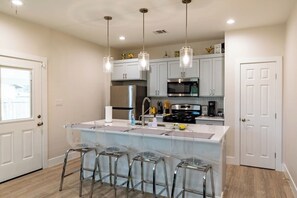 A modern kitchen with a central island, stainless steel appliances, and bar stools.
