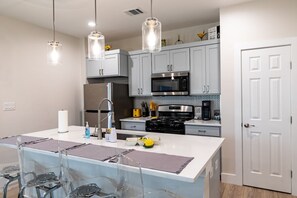 A modern kitchen with a central island, stainless steel appliances, and pendant lighting.