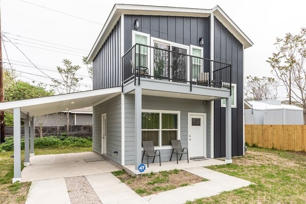 A two-story house with a covered patio, a balcony, and a small front yard.
