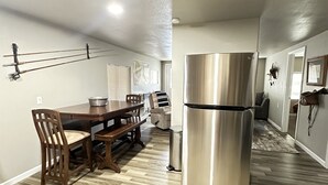 A modern kitchen with a stainless steel refrigerator, wooden dining table, and chairs. - Hooked On The River (Stites)