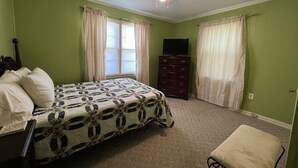 A bedroom with a bed, a dresser, a television, and a ceiling fan.