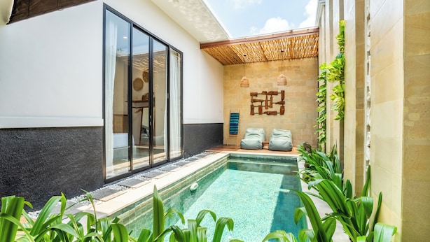 A modern pool area with a glass door entrance, stone walls, and a bamboo ceiling. - Villa Kamaratih (Legian)