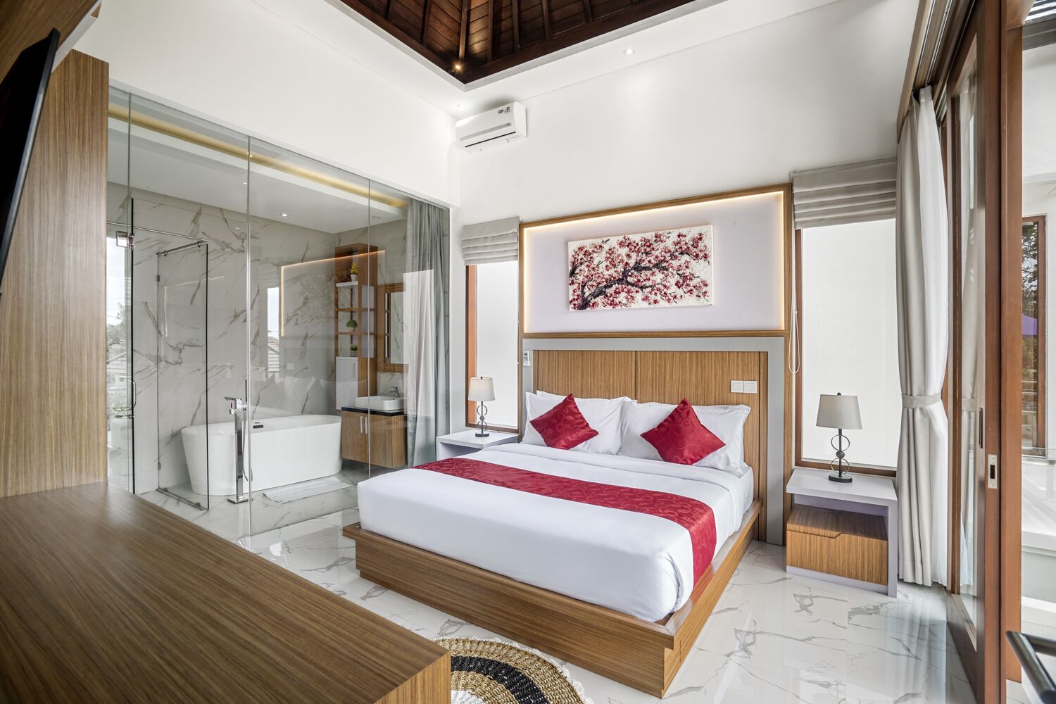 A modern hotel room with a large bed, a glass shower enclosure, a wooden desk, and a marble floor.