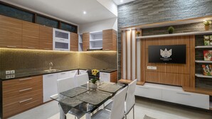 Une cuisine moderne avec des meubles en bois, un pare-feu en carrelage et un coin repas comprenant une table et des chaises en verre.