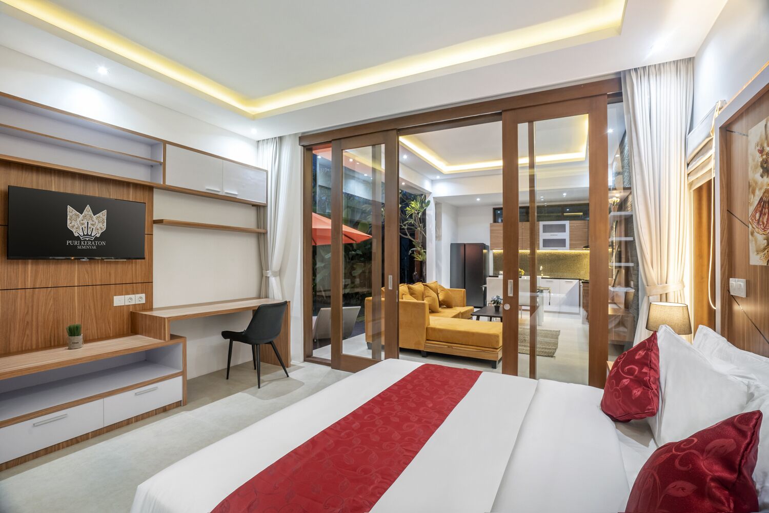 Une chambre d’hôtel moderne dotée d’un grand lit, d’un bureau, d’une télévision et d’une porte-fenêtre coulissante donnant sur un balcon.