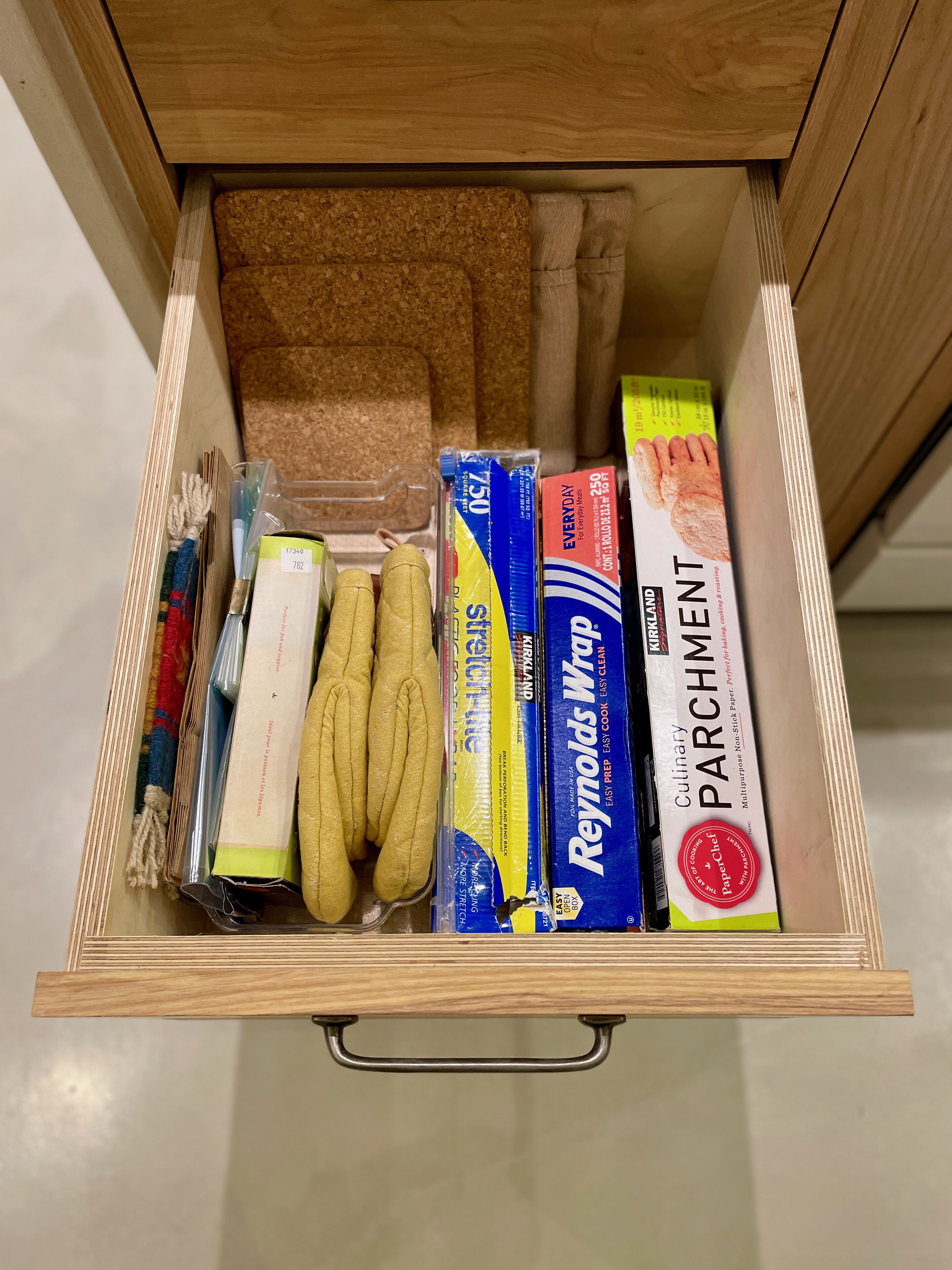 Un calaix amb articles de cuina, com ara tovalloles de paper, una placa de forn i un llibre de receptes.