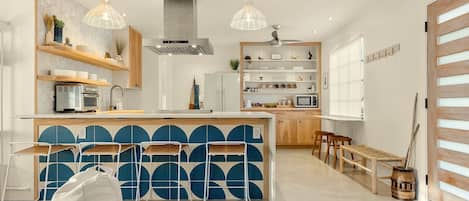Una cocina moderna con una isla central, taburetes de bar e iluminación colgante.
