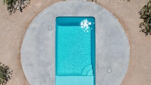 Vista aérea de uma piscina retangular com um deck circular de concreto ao redor.