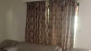A living room with a beige sofa, a glass coffee table, and patterned curtains. - Impeccable 4-Bed Villa in Mirpur azad khasmir (Mirpur azad khasmir)