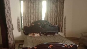 A bedroom with a dark wooden bed, patterned curtains, and a tiled floor. - Impeccable 4-Bed Villa in Mirpur azad khasmir (Mirpur azad khasmir)