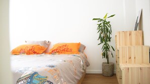 Une chambre à coucher avec un lit, deux oreillers, une plante en pot et une armoire en bois.