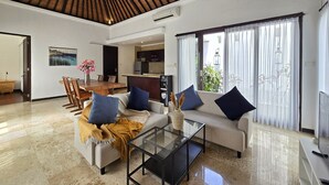 A spacious living area with a modern design, featuring a glass coffee table, a sofa with cushions, and a dining area with chairs. - Villa Jade (Ungasan)