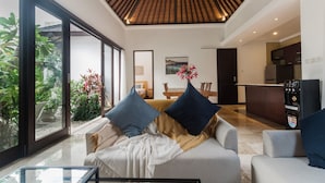 A modern living room with a sofa, coffee table, and a view of the outdoors. - Villa Jade (Ungasan)