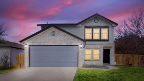 Une maison à deux étages avec un garage, un petit porche et une pelouse bien entretenue.
