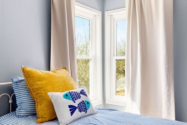 A bedroom with a bed, two windows, and curtains.