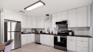 Une cuisine moderne avec des armoires blanches, des appareils en acier inoxydable et un plancher en bois clair.