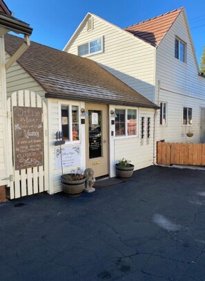 A small, single-story building with a white exterior and a brown roof. There is a sign on the door indicating it is a coffee shop. - Monte Bianco Inn (Mount Shasta)