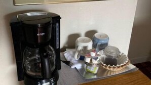 A coffee maker, a tray with jars, and a framed picture on a wooden surface. - Monte Bianco Inn (Mount Shasta)