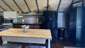 Une cuisine avec une table en bois, un réfrigérateur et un four à micro-ondes.