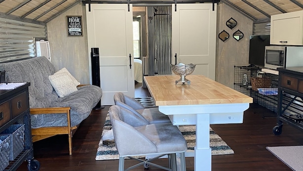 Un loft spacieux avec un plafond haut, un coin repas avec une table et des chaises, un canapé et un coin cuisine équipé d’un four à micro-ondes et de placards.