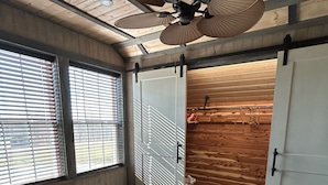 Une chambre à coucher comprenant un lit, un ventilateur de plafond, une armoire et une fenêtre avec des stores.