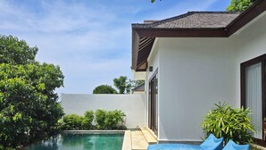 A swimming pool with a wooden deck, a blue outdoor sofa, and potted plants. - Villa Venta (Ungasan)