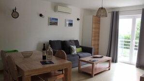 Un salon moderne avec une table à manger en bois, un canapé et une table basse. Il y a une horloge au mur et une fenêtre avec des rideaux.
