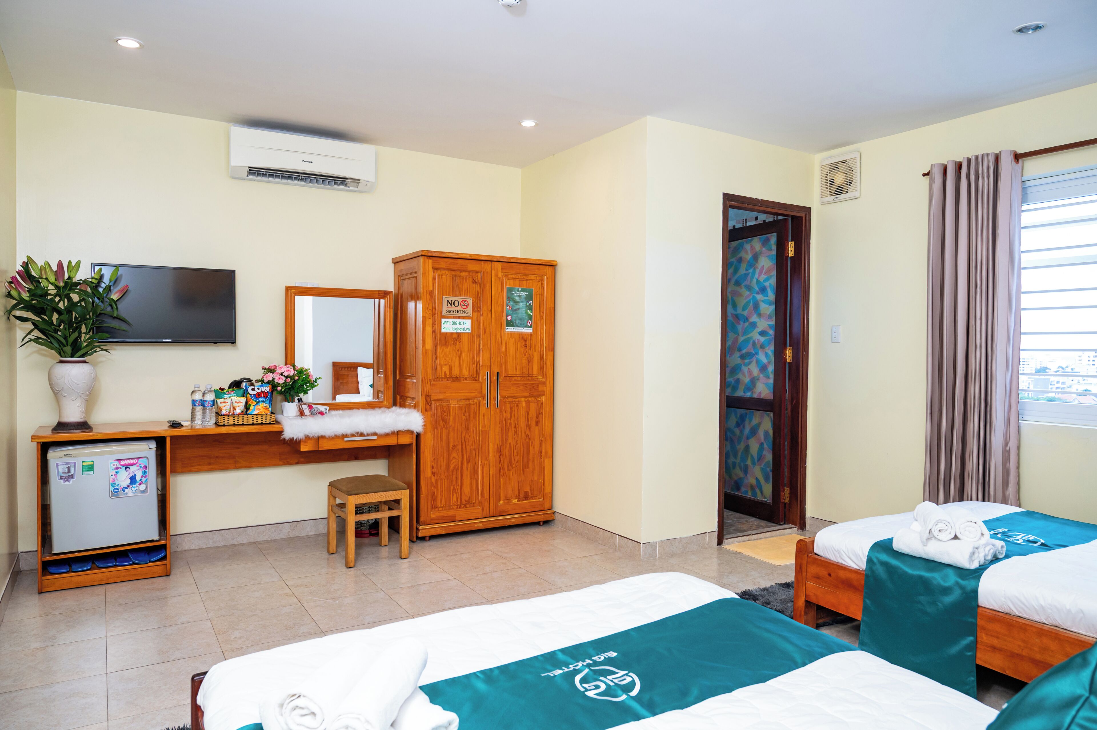 A hotel room with a bed, a desk, a wardrobe, a television, and a refrigerator.