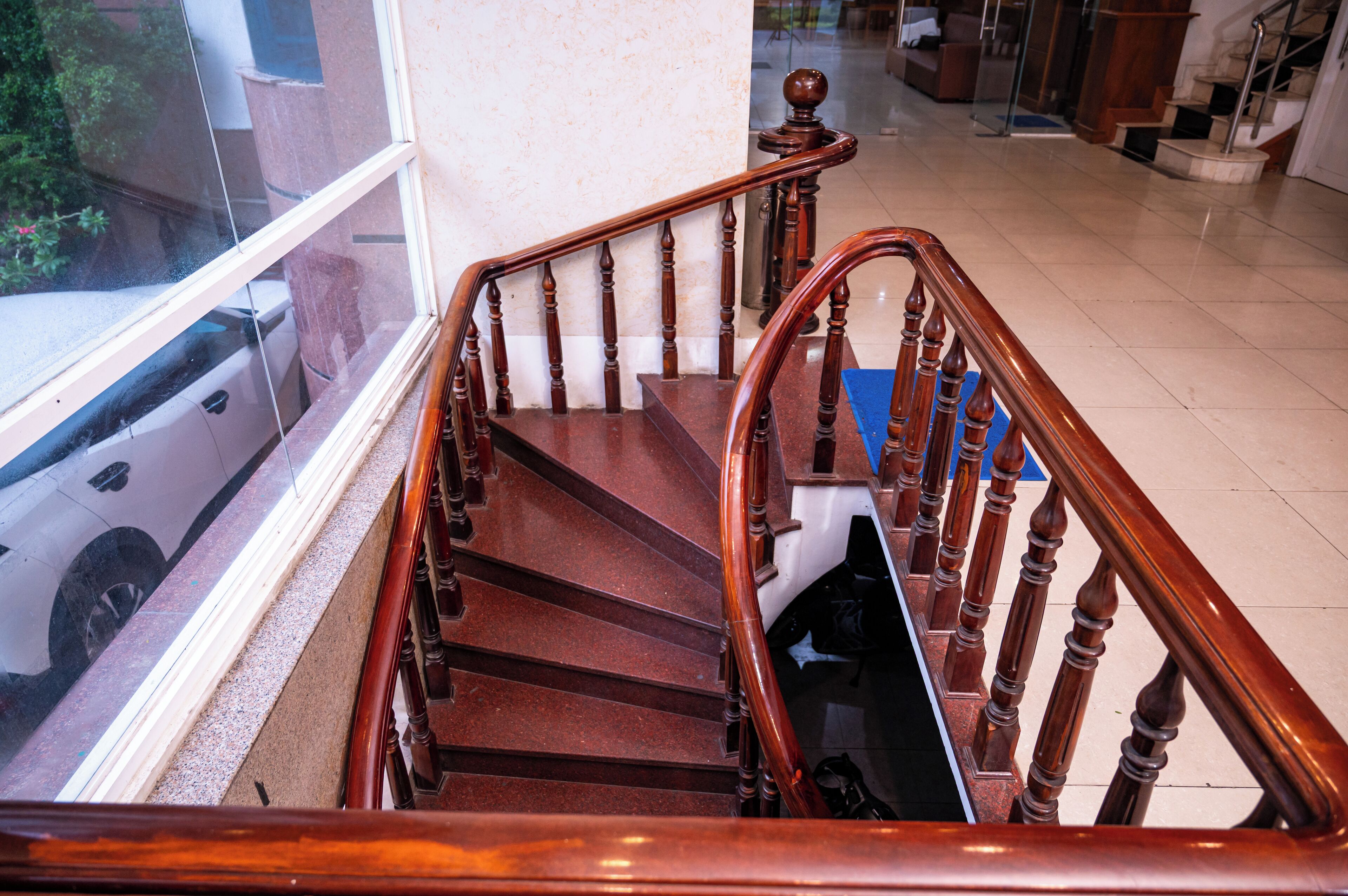 A wooden staircase with a handrail, leading to a landing with a blue mat.
