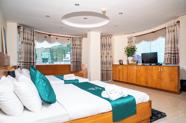Quarto de hotel com duas camas, televisão, armário e janela com cortinas.