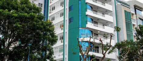 A multi-story hotel with a green and white facade, balconies, and a sign indicating it is a group hotel.