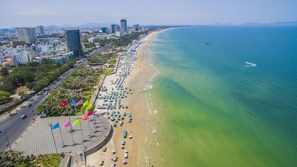 An aerial view of a coastal city with a long beach, clear blue waters, and a mix of residential and commercial buildings. - BIG HOTEL VUNG TAU  (Ho Chi Minh City)