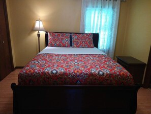 Cozy retreat with a single bed, nightstand, and lamp, featuring a patterned bedspread and two matching pillows.