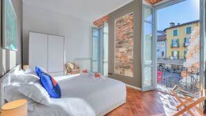 Ein Hotelzimmer mit einem großen Bett, Blick auf die Straße und einem Balkon mit Sitzgelegenheit.