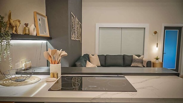 A modern kitchen with a built-in induction cooktop, a digital display, and a marble countertop.