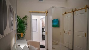 A bedroom with a bed, a bedside table, a potted plant, a wardrobe, and a television.