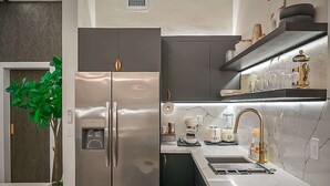 A modern kitchen with a built-in refrigerator, a sink, and a coffee machine.
