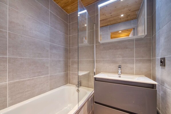 Ein modernes Badezimmer mit einer Duschkabine, einer freistehenden Badewanne und einem Waschtisch mit Spiegel.