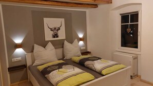Une chambre avec deux lits, un tableau représentant une tête de taureau accroché au mur, et deux lampes fixées au mur.