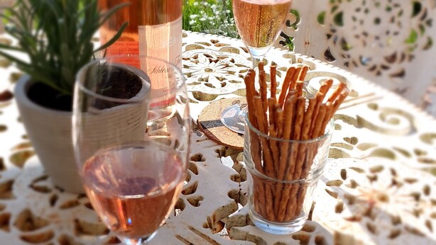 Une table avec une bouteille, un verre et un récipient en verre contenant des bâtonnets.