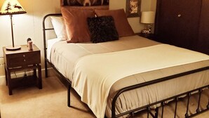 A single bed with a metal frame, a bedside table with a lamp, and a bear-themed wall decoration. - Beautiful, Quiet Condo in Keystone! (Keystone)