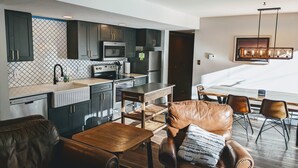 A modern kitchen with dark cabinets, a microwave, and a stove. There is a dining area with a wooden table and leather chairs. - Beautiful, Quiet Condo in Keystone! (Keystone)