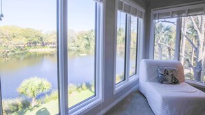 A room with large windows offering a view of a lake and trees.