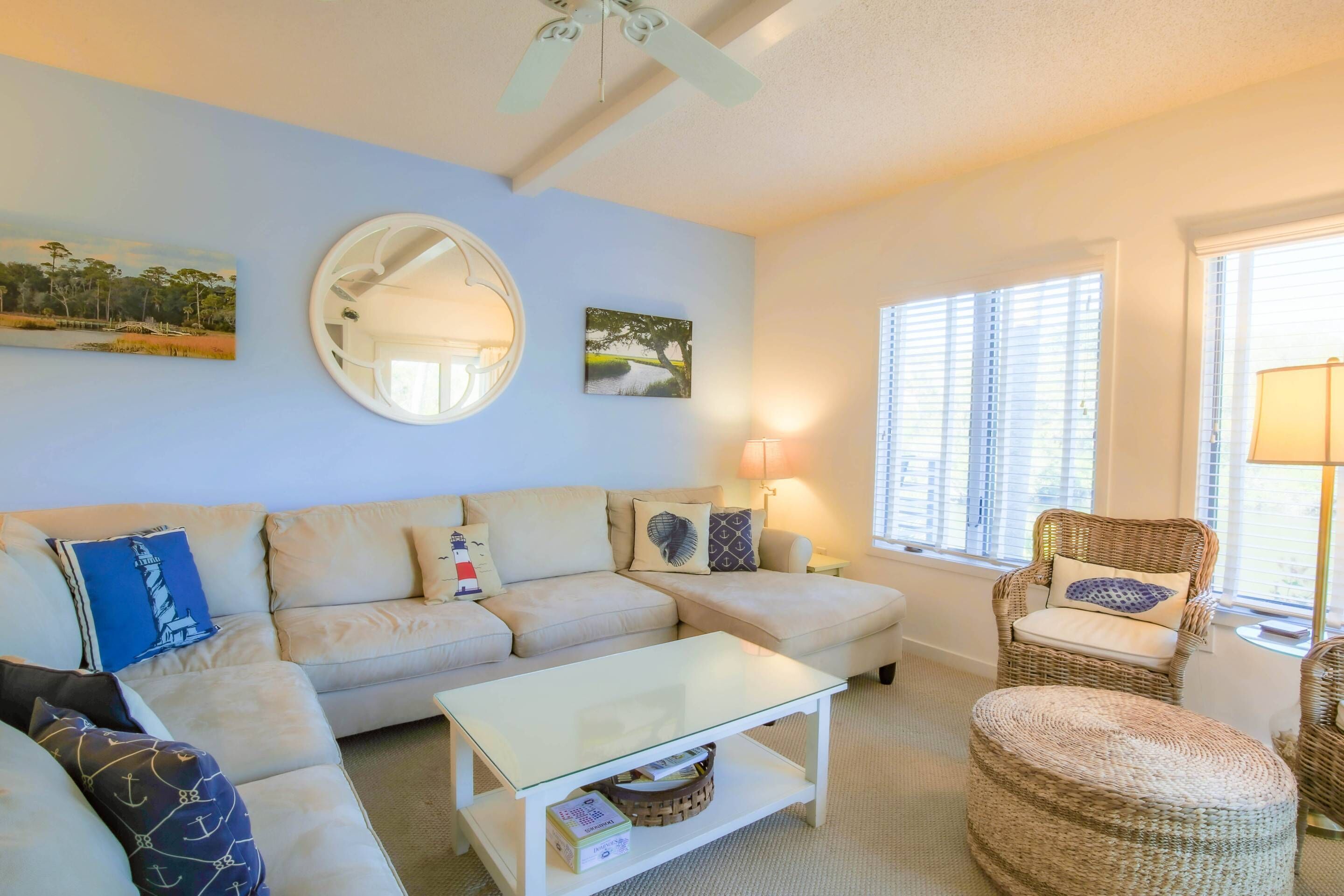 A living room with a beige sofa, a round mirror, and a wicker chair.