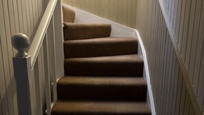 A carpeted staircase with white railings and a white balustrade. - Hugh’s Highland Hideaway (Culnacnoc)